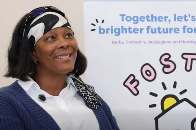 A smiling woman with dark hair and a black and white patterned headband looks up and to the right, with a banner behind her that reads "Together, let's build a brighter future for... Derby, Derbyshire, Nottingham and Nottinghamshire" and "FOSTER".
