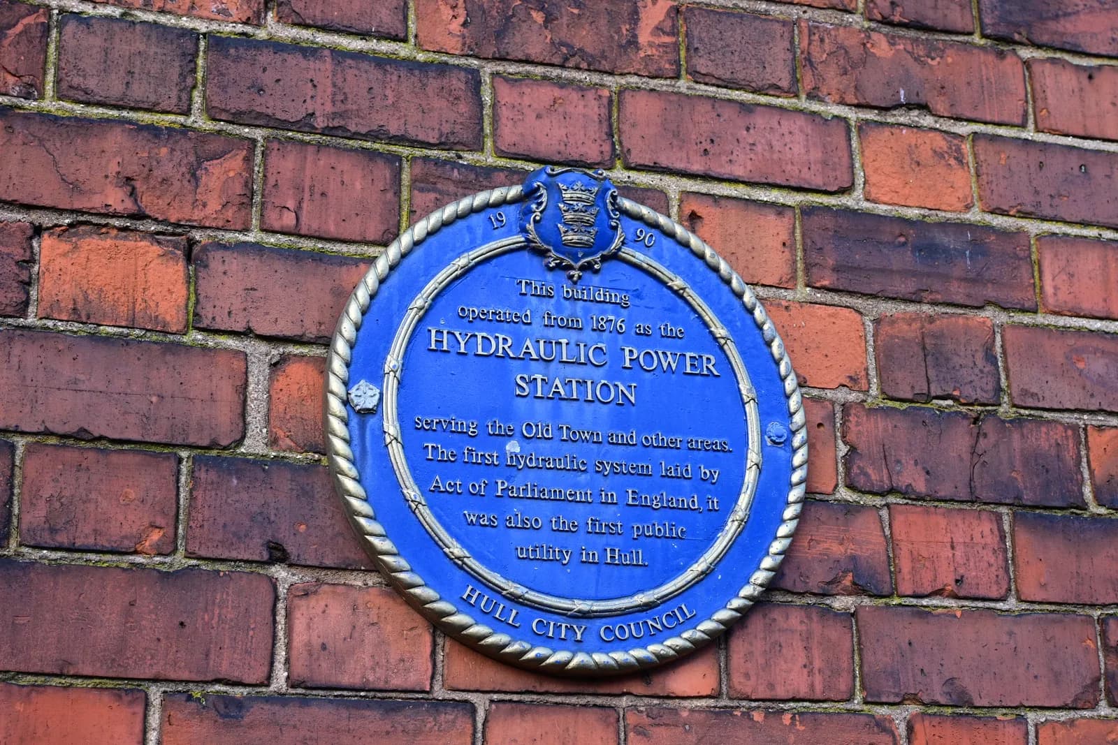 A blue plaque on a brick wall details the history of the Hydraulic Power Station, noting its operation from 1876 and its role as Hull's first public utility.
