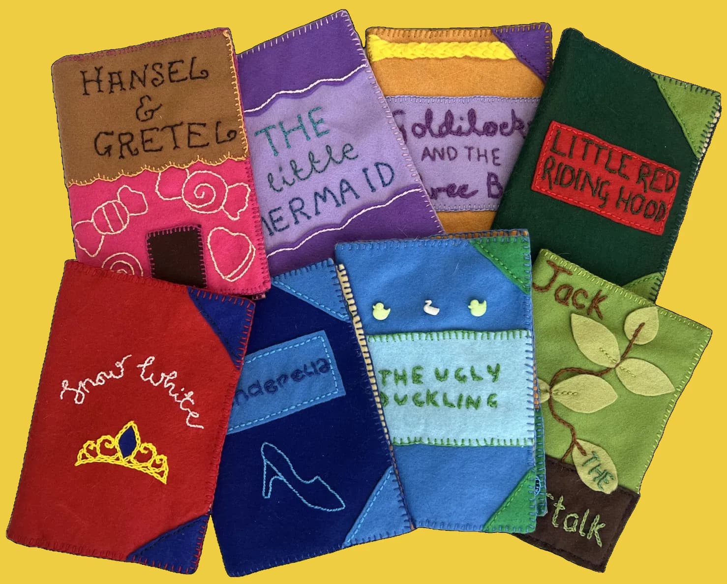 A collection of colorful felt storybook covers for classic fairy tales like Hansel & Gretel, The Little Mermaid, Goldilocks, Little Red Riding Hood, Snow White, Cinderella, The Ugly Duckling, and Jack and the Beanstalk.