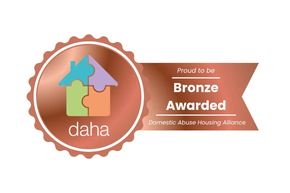A bronze award logo with a puzzle piece house icon and text that says "Proud to be Bronze Awarded, Domestic Abuse Housing Alliance".