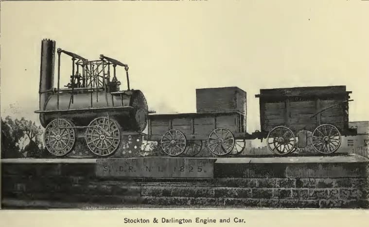 A black and white engraving depicts an early 19th-century steam locomotive pulling two open-top freight cars, on a brick wall with text.