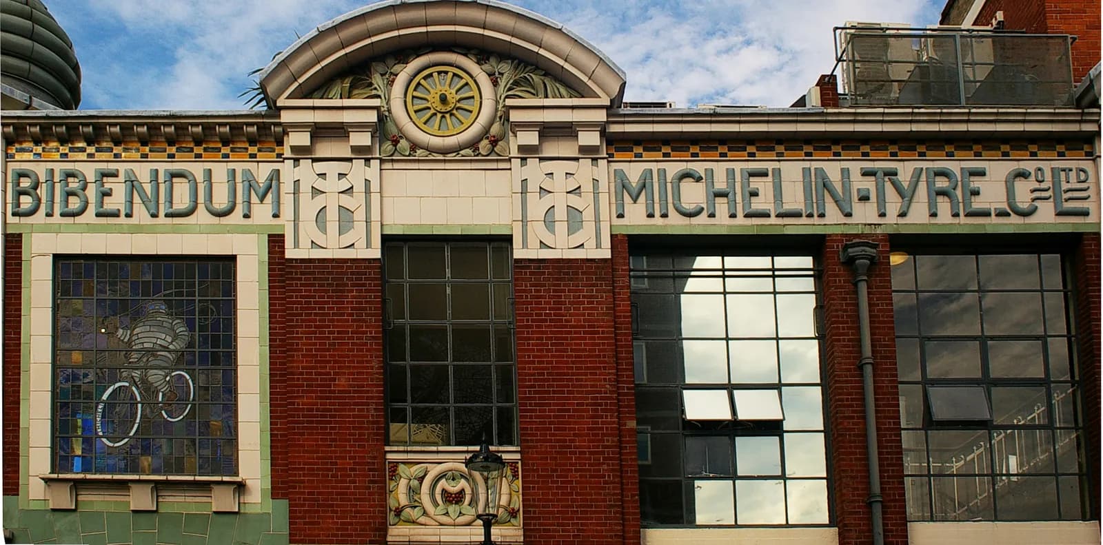 A close-up shot of the facade of the Bibendum Michelin-Tyre building, with ornate detailing, brickwork, and windows reflecting the sky.