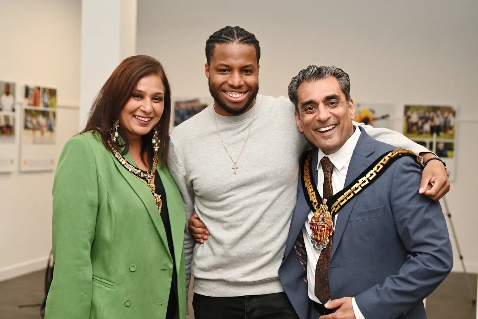 Three people, two men and one woman, are posing for a photograph together, all smiling and looking directly at the camera.