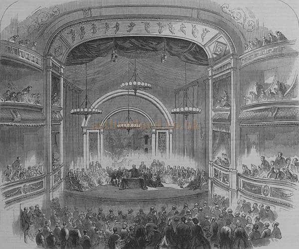 A 19th-century engraving of a large gathering in a theater, with a speaker addressing an audience from a stage and many people filling the surrounding balconies and main floor.