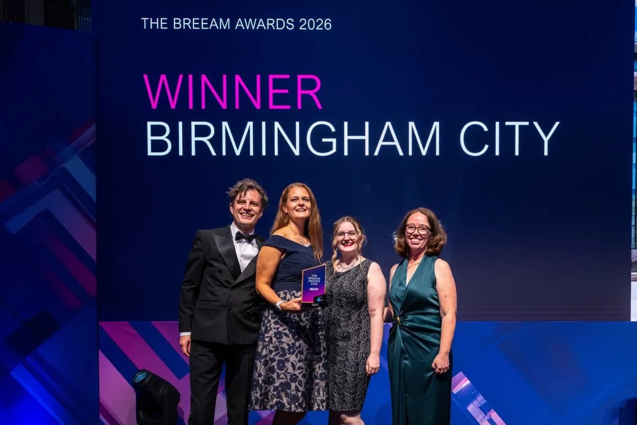 Four people, two men and two women, smiling at the camera while holding an award on a stage with a screen behind them displaying "WINNER BIRMINGHAM CITY".