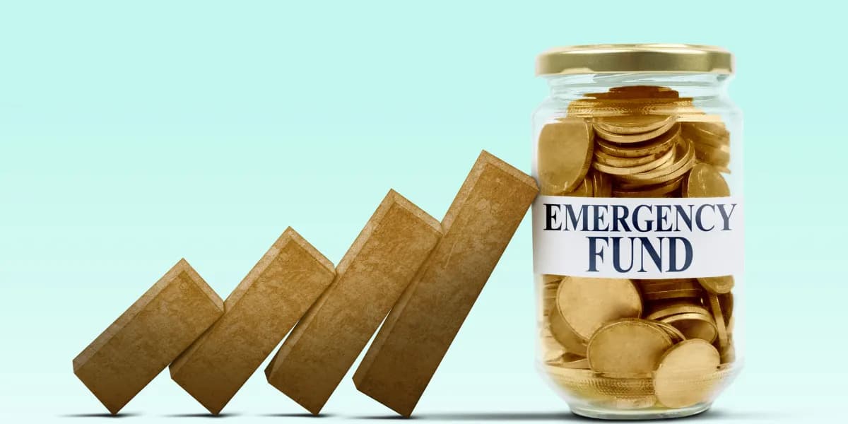 A glass jar filled with gold coins labeled "EMERGENCY FUND" stands next to a line of dominos, representing potential financial instability.