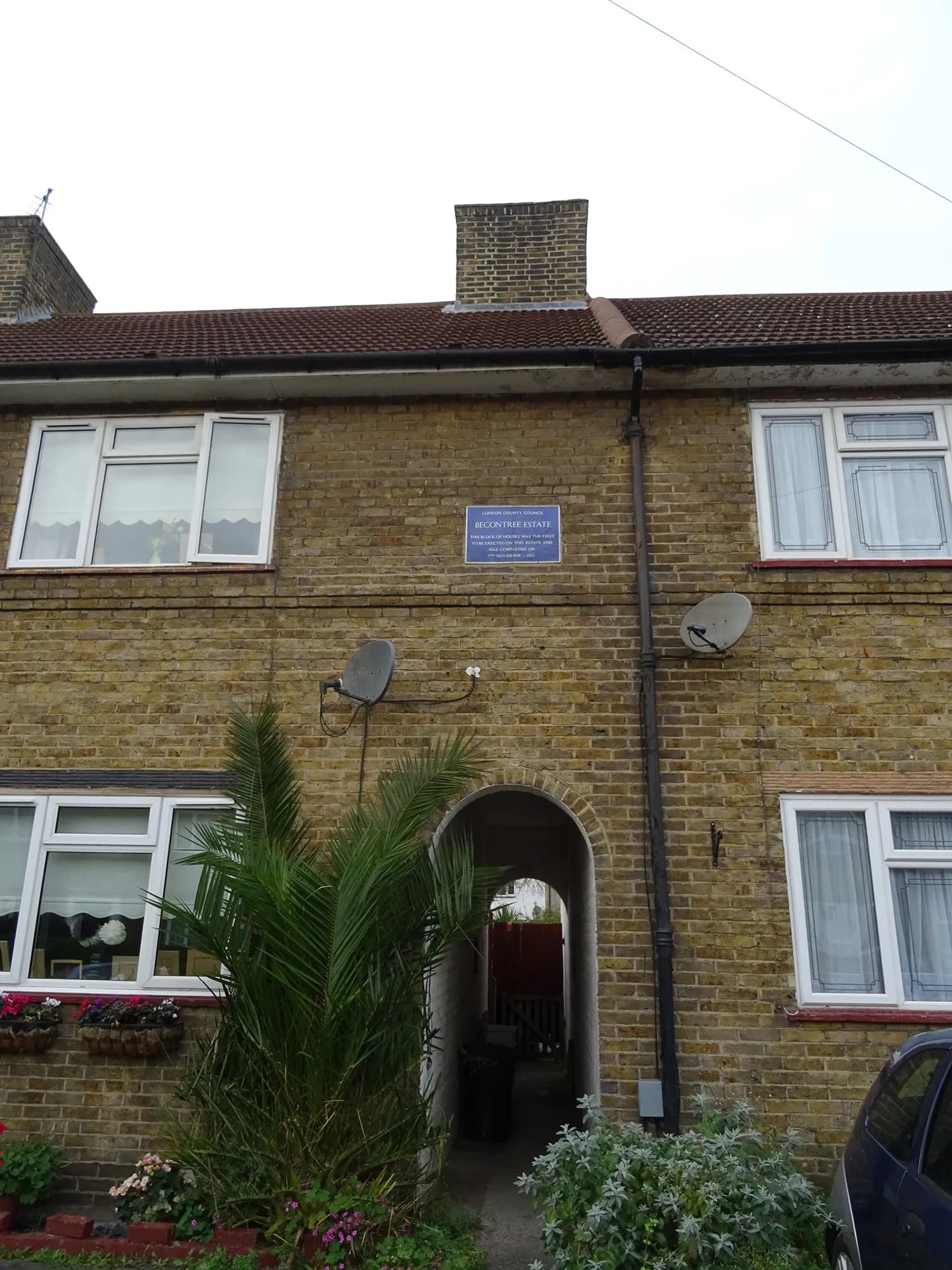 A close-up view of the exterior of a brick building with a blue sign and archway on the ground floor.