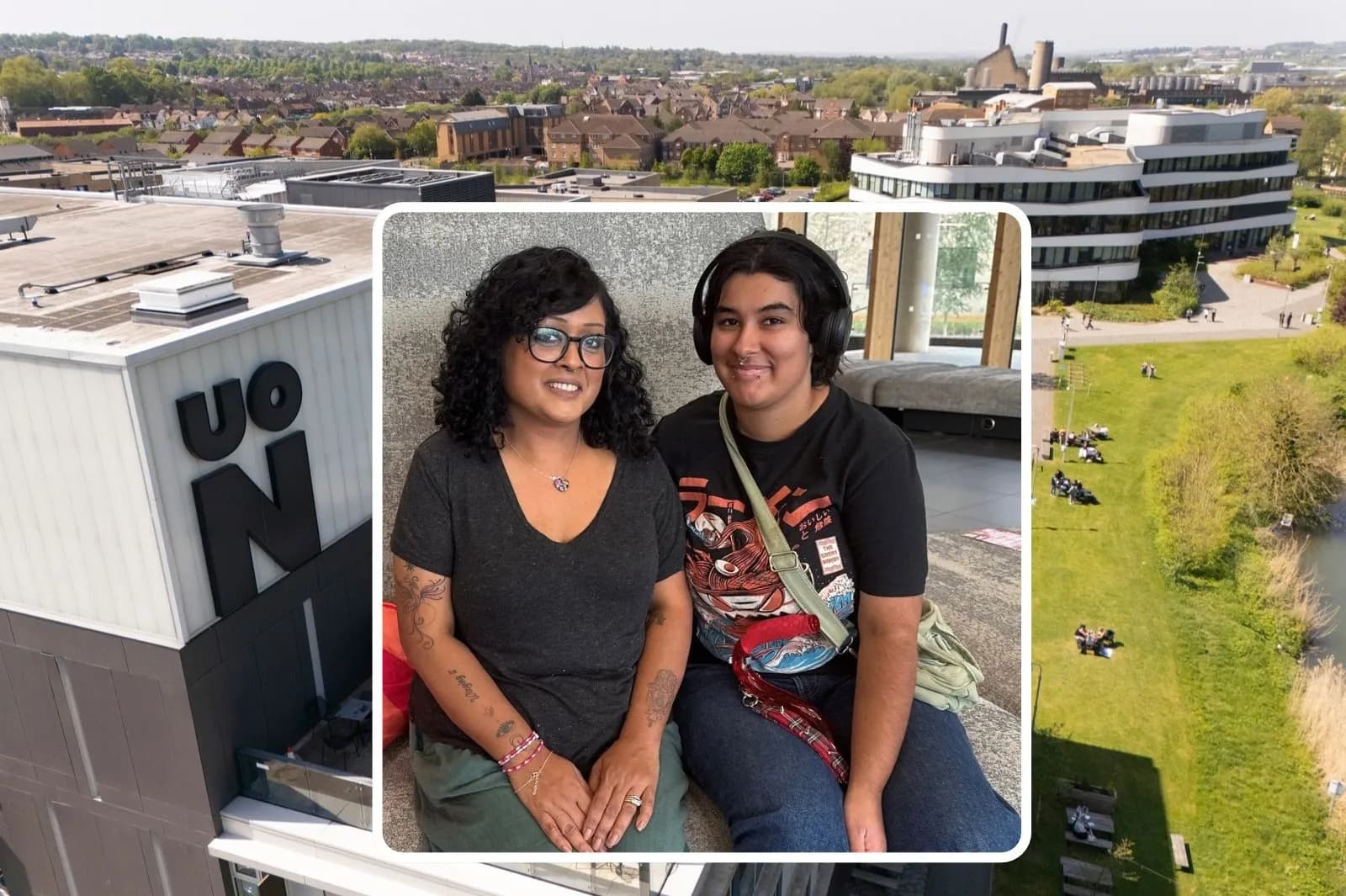 Two women, one with curly hair and glasses, and another with headphones, smile while sitting together, overlaid on an aerial view of a university campus with buildings and green spaces.