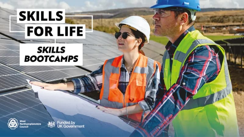 Two engineers, a man and a woman, wearing safety vests and hard hats, are examining blueprints on solar panels at a solar farm.