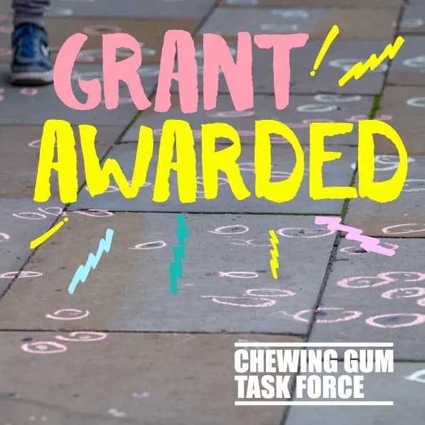 A child's legs and feet are visible at the top left of the image, walking on a pavement with chalk drawings of circles and zigzags. The words "GRANT AWARDED" are written in large, bright pink and yellow letters across the center of the image, with "CHEWING GUM TASK FORCE" in smaller white letters at