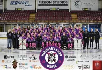 A large group of women wearing purple and black hockey uniforms pose on an ice rink, with a few male coaches in dark suits standing at the sides, all in front of empty red arena seating.