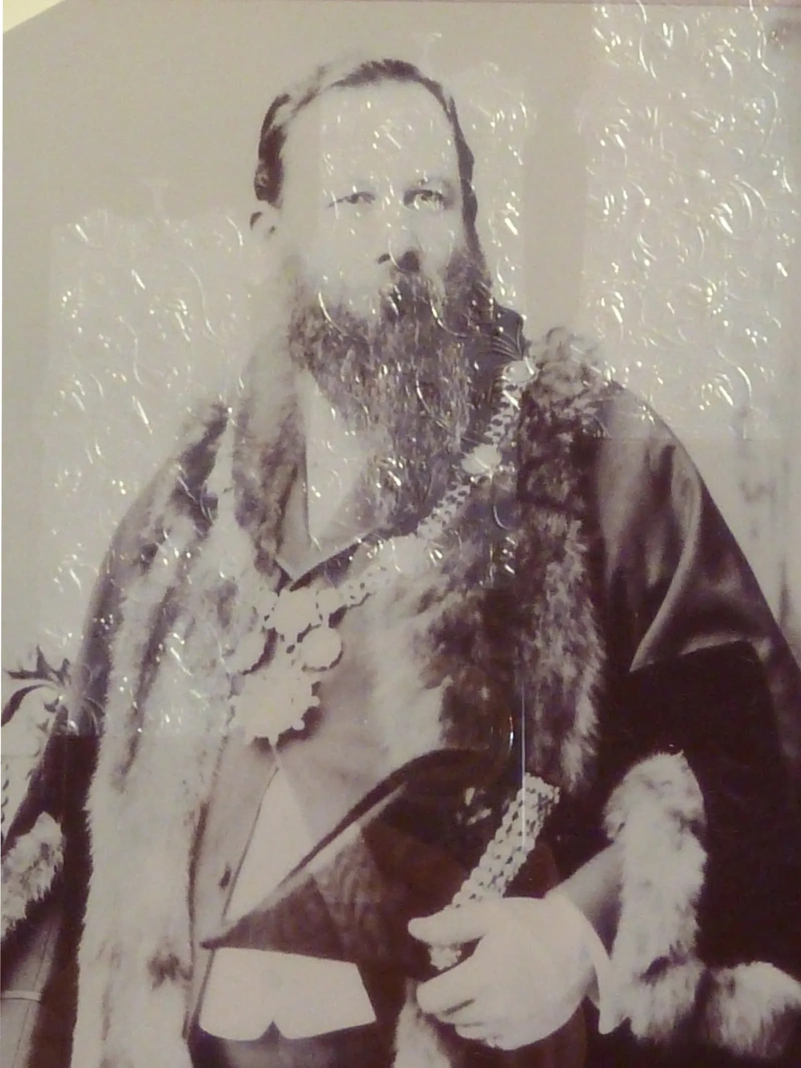 A black and white portrait of a bearded man wearing a fur-collared robe and a ceremonial medallion.